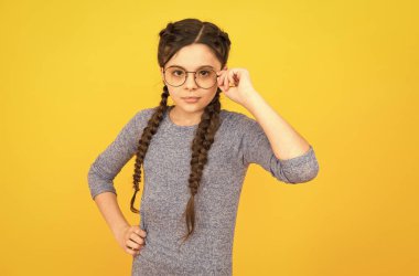 Moda gözlüklerini seçmesi tarzı için mükemmel. Küçük çocuk sarı gözlük takıyor. Sıradan tarzda küçük bir kız. Moda tarzı. Şık bir gözlük. Güzellik bakışı. Kuaför salonu. Heyecan verici biçim