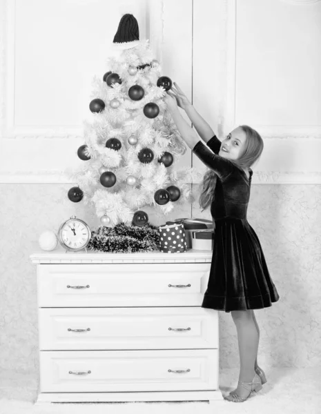Kids can brighten up christmas tree by creating their own ornaments. Girl celebrate christmas. Top christmas decorating ideas for kids room. Child hang christmas ornament ball on artificial tree — Stock Photo, Image