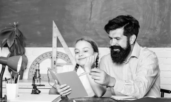 Schoolgirl holding lesson book. education child development. bearded man teacher with small girl in classroom. knowledge day. Home schooling. back to school. daughter study with father. Teachers day — Stock Photo, Image