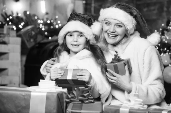 快乐和快乐。快乐的家庭庆祝新年。快乐的圣诞节。母亲和女儿都喜欢度假。带着妈妈戴着圣诞礼帽的小女孩。圣诞节礼品盒。打开礼物。冬季采购销售 — 图库照片