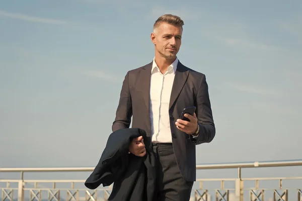 Traje formal de hombre de negocios con smartphone. Concepto de vida moderna. Jefe en camino a la oficina. Utilice el teléfono mientras camina. Estilo urbano. Día de trabajo regular. Hombre carismático cielo azul fondo. Llamada telefónica — Foto de Stock