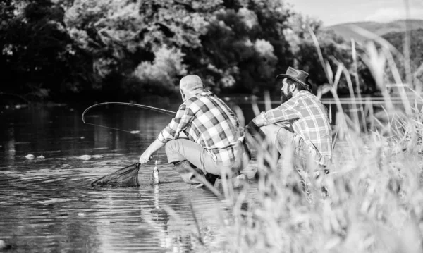 Due amici maschi che pescano insieme. pesca d'altura. rilassarsi sulla natura. Buona amicizia tra pescatori. padre in pensione e figlio barbuto maturo. hobby di pesce di mosca di uomini. pesca a riposo. L'abbiamo preso. — Foto Stock