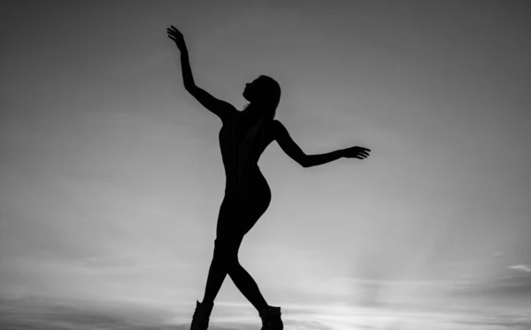 Female silhouette on sunset sky background of dancing woman, silhouette Stock Picture