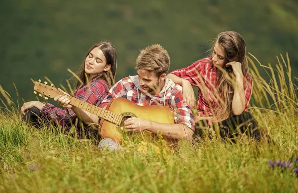 Folk kopplar av på bergstoppen medan stilig man spelar gitarr. Lugnt ställe. Naturens melodi. Vandringstradition. Vänner vandrar med musik. Sjunger tillsammans. Musikpaus. Vandringsunderhållning — Stockfoto