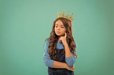 Düşünceli bebek. Küçük hanım prenses. Kız taç takıyor. Prenses terbiyesi. Güzellik yarışmasının galibi. Uluslararası güzellik yarışması. Çocuk prensesin altın taç sembolünü takıyor. Prenses ol.
