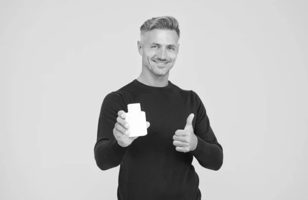 Gelukkig aantrekkelijke man in casual stijl show duimen ups hand gebaar houden eau de toilette gele achtergrond, knap — Stockfoto