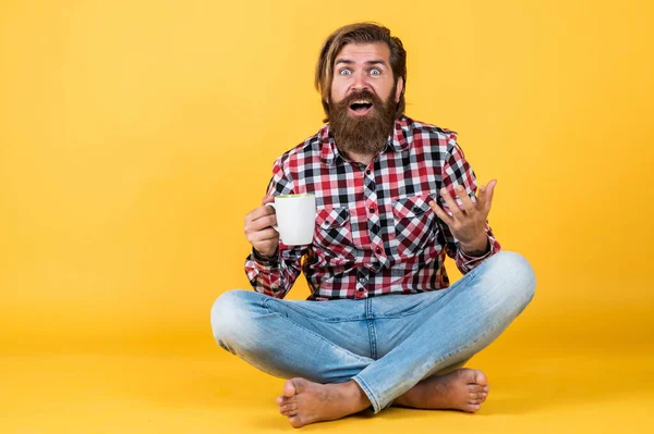 Удивленный красивый бородатый парень с небритым лицом и стильной прической носить повседневную одежду пить кофе, сюрприз — стоковое фото