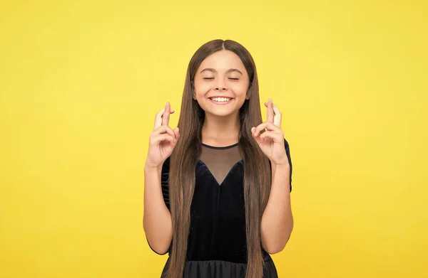 Close your eyes and make a wish. Happy child cross fingers yellow background. Wish and hope. Trust in magic or chance. Superstition and belief. Lets dream