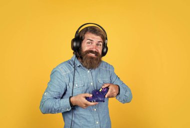 Hayatını Game ile süsle. Neşeli adam modern kulaklık takıyor. Oyun konsollu kulaklıklı bir erkek. Bilgisayar oyunu konsepti. İnternette oynuyor. En sevdiğin hobiyle rahatla. Sakallı adam oyuncu.