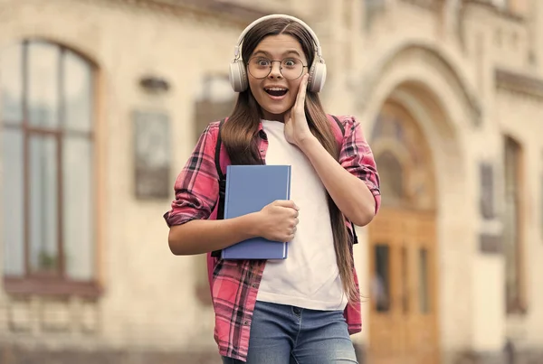 Amazing audio content. Surprised child listen to audio book outdoors. Audio lesson. New technology. English school. Learning foreign language. Modern life. Music education. All you need are your ears
