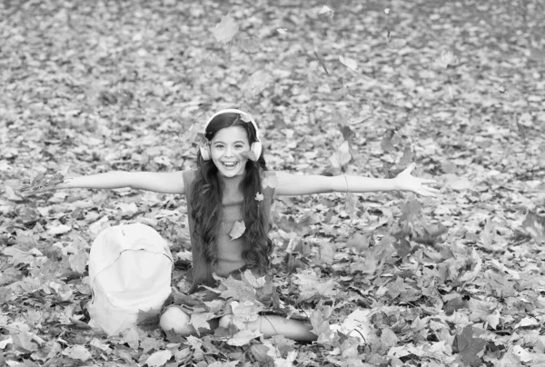 Щаслива дівчина в гарному настрої викидає осіннє листя, шкільний час — стокове фото