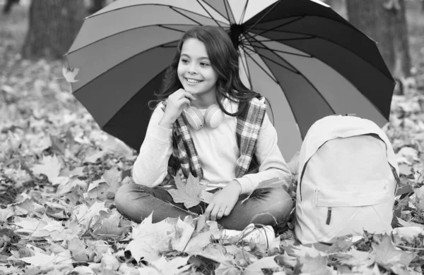 Recuerdos desgarradores. disfrutar de clima cálido de temporada. niño feliz sentado bajo paraguas colorido. chica con mochila bajo protección contra la lluvia. niño relajarse en el bosque de otoño. El otoño sale en el parque. de vuelta a la escuela — Foto de Stock