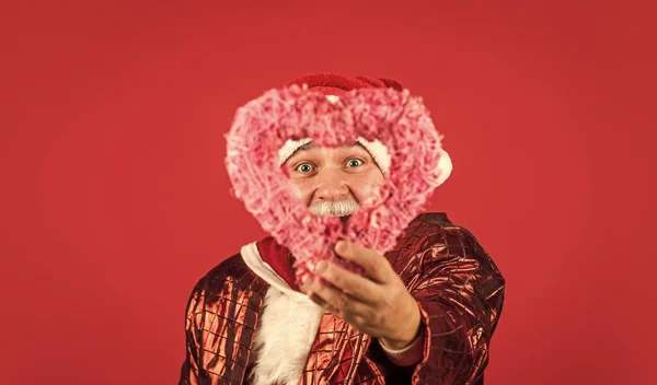 Facciamolo e basta. felice anno nuovo 2021. Buon Natale a tutti. Babbo Natale barbuto in cappello tenere cuore decorativo. regali di Natale e tempo di shopping regalo. vacanza invernale gioia. Amore. divertente uomo anziano in costume di Babbo Natale — Foto Stock