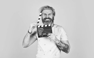 Sakallı adam film alkışlayıcısı tutuyor. Film yapma konsepti. Alkış tahtası kopyalama alanı. Film izle. Film yönetmeni. Oyuncu kadrosu. Çekim sahnesi. Favori dizisi. Başla. Sinema yapımı. Yaratıcı yapımcı