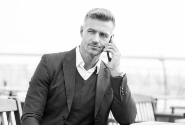 Açık kafede, cep telefonunda resmi konuşmalar yapan ciddi konuşmacı.