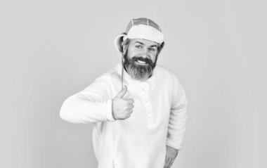 Olgun bir adam komik kıyafetiyle poz veriyor. Kış şapkalı adam sakalı. Şapka takan trend bir adamın portresi. Erkek kış tarzı. Modern kış kulaklığı şapkası. Komik, mutlu, sakallı adam. Kutlamadan önce