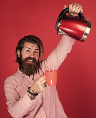 Hadi bir şeyler içelim. Sıcak suya ihtiyacım var. Adam çay ya da kahve içecek. Bıyıklı ve sakallı vahşi bir adam. Elektrikli ev aleti. Sakallı adam kırmızı elektrikli su ısıtıcısı kullanıyor. erkek ev idaresi kavramı