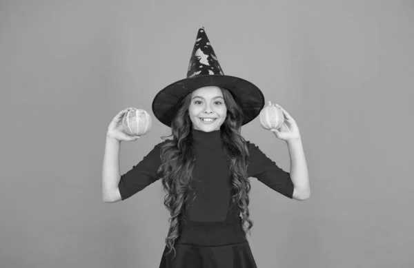 Enfant heureux avec des cheveux longs porter chapeau sorcière tenir citrouille pour Jack o lanterne à la célébration des vacances d'automne, Halloween heureux — Photo