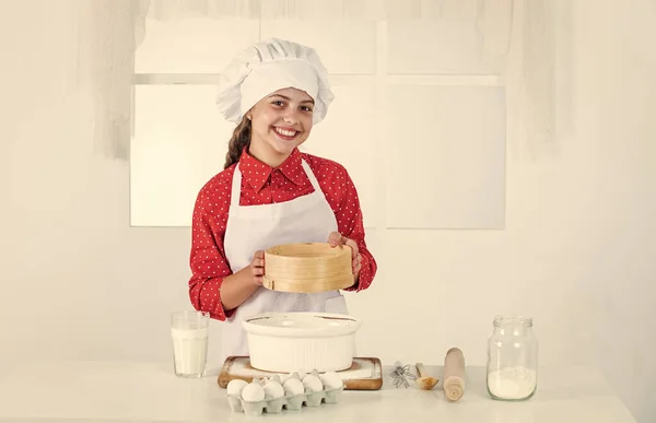 Mädchen sieben das Mehl durch ein Sieb, Küche — Stockfoto