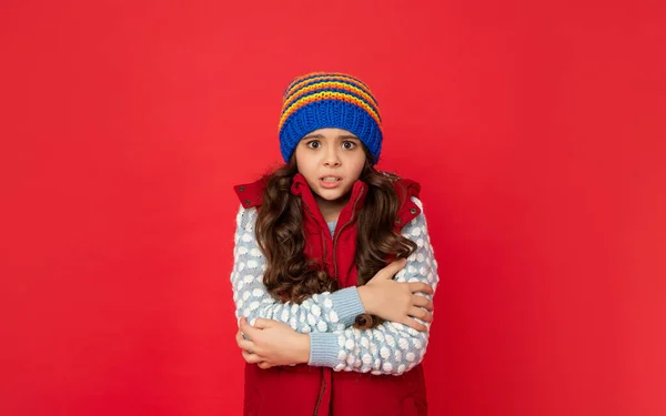 ティーン女の子感じ寒いですでニット冬の帽子とダウンベストで赤の背景,寒い季節 — ストック写真