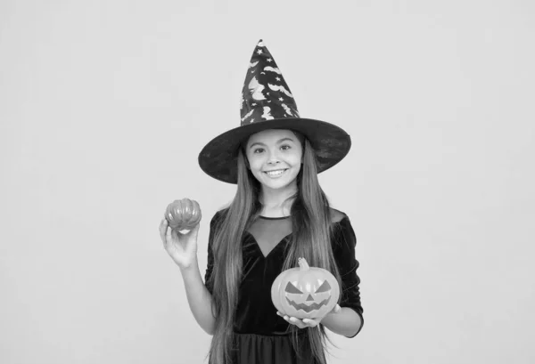 Criança feliz usar chapéu de bruxa segurando abóbora para criar jack o lanterna no dia das bruxas, tradição halloween feliz — Fotografia de Stock