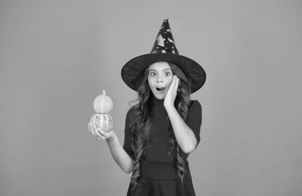Meglep, hogy boszorkánykalapot visel. gyermek kis sütőtökkel. tini lány hosszú göndör haj és ruhát viselni a party ünneplés. Őszi szünet. Gyerekkori szabadidő. Töklámpás. Boldog Halloweent! — Stock Fotó