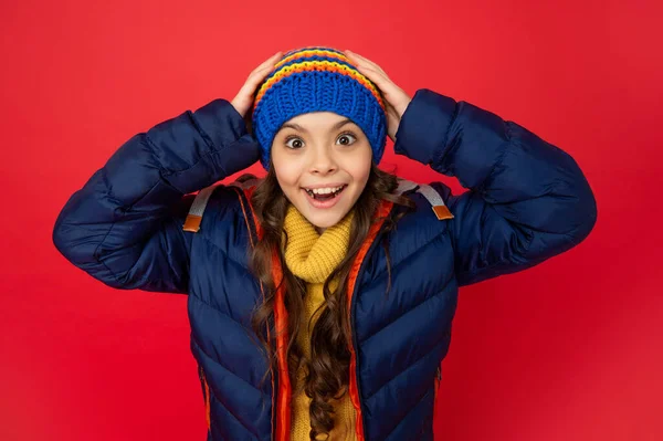 Εκφράζω θετικό συναίσθημα. χειμερινή μόδα. έκπληκτος παιδί με σγουρά μαλλιά κρατώντας καπέλο. — Φωτογραφία Αρχείου
