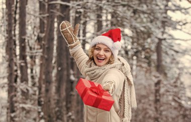 Noel Baba yardımcısı. Kış alışverişi. hediye ve sürpriz konsepti. Herkese mutlu noeller dilerim. Yeni yılınız kutlu olsun. Noel tatili. Hediye zamanı. Kırmızı Noel Baba şapkalı kadın hediye kutusunu tutuyor. Boks günü