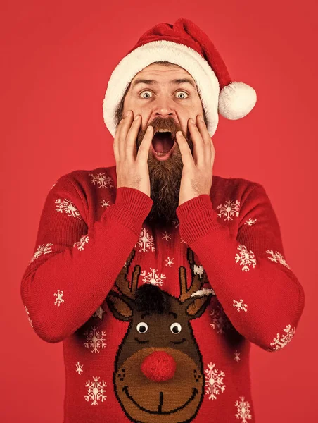 Hombre sorprendido con barba en sombrero de Santa Claus. hipster barbudo en jersey de Navidad. fiesta de invierno. compras en línea de Navidad. brutal hombre de fondo rojo. chico maduro celebrar año nuevo —  Fotos de Stock