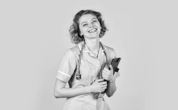 Επαγγελματίας γιατρός κρατάει φάκελο. Χαρούμενη νεαρή νοσοκόμα κρατώντας πρόχειρο. Οι γυναίκες γιατροί χρησιμοποιούν στηθοσκόπιο. θεραπευτής με στολή στο νοσοκομείο. ιατρικό ιστορικό και συνταγή — Φωτογραφία Αρχείου