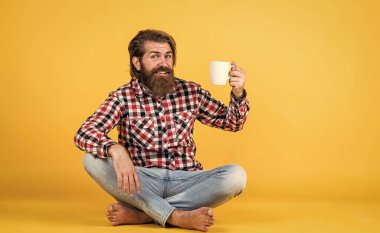Bunu dene. Adam fincandan sıcak çay içiyor. Sana da günaydın. Enerjik, sıcak bir içecek. İlham için biraz kahveye ihtiyacım var. Güne mükemmel bir başlangıç. Mutlu sakallı adam sabah kahvesini içiyor.