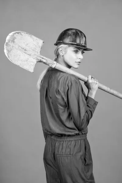 작동하게 합시다. 노동의 날입니다. 보일러 수트와 헬멧을 쓰고 있는 여성. 여자 건축자가 삽을 들고 있다. — 스톡 사진