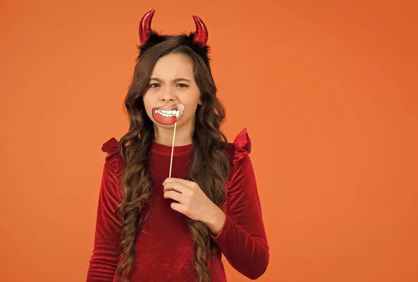 Garoto confuso com cabelos longos usar chifres do diabo segurar acessório de festa engraçado para a celebração do feriado do outono halloween, feliz halloween — Fotografia de Stock