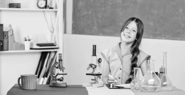 サンプルのテスト。ラボのフラスコのある小さな女の子。顕微鏡を使った科学の授業。学校の研究室。現代の技術。女の子は試験管で化学を勉強する。学校に戻って。生物学教育 — ストック写真