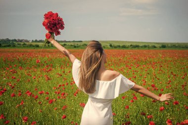 Haşhaş tarlasında beyaz elbiseli mutlu bir kız yaz günbatımında, tatil zamanı