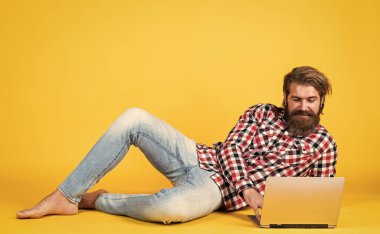 Rahatlama zamanı. Kareli tişörtlü sakallı adam internette ders dinliyor. Webinar ve iş eğitimi. Laptop kullanarak. Online öğrenme kavramı. Sosyal mesafe. Not defterli özenli adam.