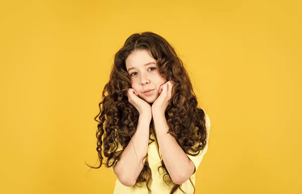 Hermosa modelo. Rizos saludables. Cabello largo. Peinado fácil. Artículos de belleza. Desenreda perfectamente el cabello rizado. Chica bonita pelo rizado fondo amarillo. Peluquería. Adorable niño pequeño — Foto de Stock