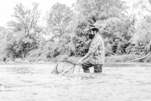 Na aposentadoria. Feliz pescador barbudo na água. homem maduro voar pesca. Homem a pescar peixe. pescador mostrar técnica de pesca usar haste. Fim de semana. Pesca com mosca. hobby e atividade esportiva — Fotografia de Stock