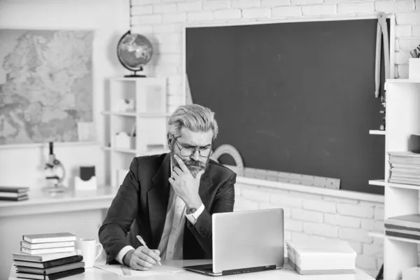 Handsome hipster mature smart educator. Use laptop and internet. Officially submitted application online. School homework. Back to school. Knowledge day. Man work school teacher sit in classroom — Stock Photo, Image