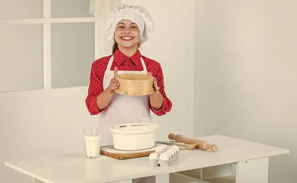 좋은 하루되 세요. 전문적 이고 숙련 된 제빵사죠. 셰프 복장에 모자쓴 애. 반죽을 준비하는 십 대 소녀. 레시피로 케이크를 만드는 것입니다. 먹을 시간이야. 부엌에서 요리하는 행복 한아이. 부엌에 있는 빵 쿠키 — 스톡 사진