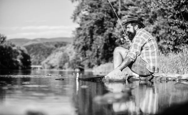 Чоловік ловить рибу. Людина на березі річки насолоджується мирним ідилічним пейзажем під час риболовлі. Хлопець літає на риболовлю. Успішне риболовля. Хобі за душу. Об'єднаний з природою. Рибалка риболовля техніка використання стрижня — стокове фото