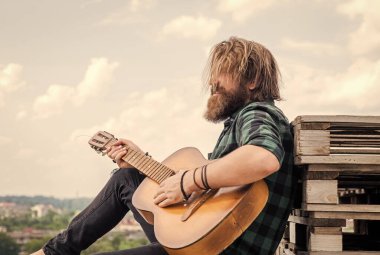 Rahatlama zamanı. Kareli gömlekli sakallı adam şarkı söylüyor. Müzisyen müzisyen. müzik teli enstrümanı. Olgun karizmatik erkek gitarist. Sakallı ve bıyıklı adam gitar çalıyor.