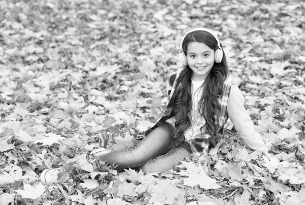 秋天的童装。灵感。快乐的童年回学校去在枫叶中的女孩在公园里放松一下。落得森林之美。喜欢耳机里的音乐。网上教育和电子学习 — 图库照片