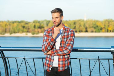 Dişli gömlekli, sakallı, genç bir adam.