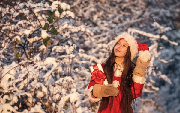 Enfant fille heureuse en plein air nature enneigée. Joyeux Noël. Joyeux concept d'enfance. Bonheur et joie. Chapeau de père Noël. Cadeaux du Père Noël. Frosty matin de Noël. C'est l'heure des miracles. Père Noël généreux — Photo