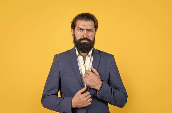 Portrét obchodníka uspořádání jeho obchodní bunda na žlutém pozadí s vousy a knírem, kancelářská móda — Stock fotografie