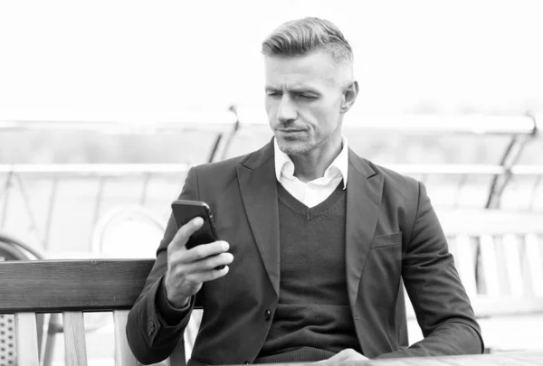 Guapo abogado leer el mensaje de negocios en el teléfono móvil sentado en el banco al aire libre, sms — Foto de Stock