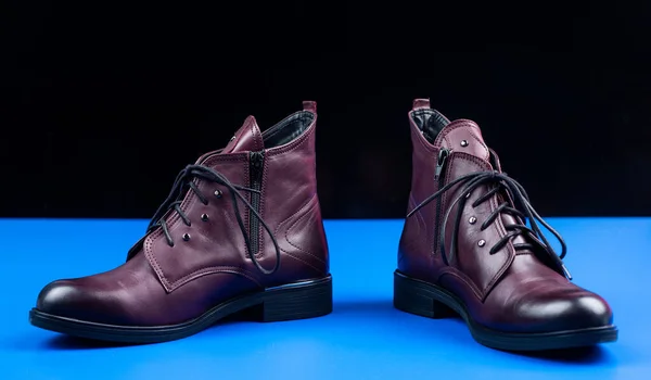 Модные кожаные сапоги со шнурками на синем фоне, обувь — стоковое фото