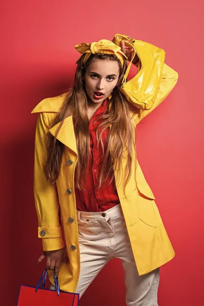 Mode meisje in gele jas houden boodschappentassen, grote verkoop — Stockfoto