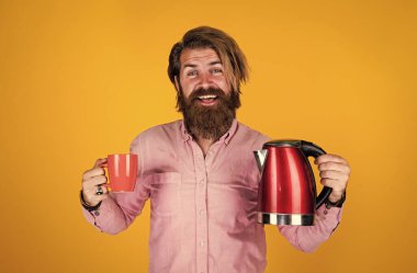 İçelim. Sakallı, çay içen olgun bir hippi. Elektrikli su ısıtıcısı olan vahşi bir adam. Gününü ısıt. Sakallı adam. Sıcak içecek iç. Mutfak gereçlerini sunuyorum. iyi kalite